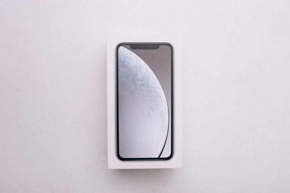 Still life editorial tech: smartphone, consola de videojuegos y reloj inteligente dispuestos sobre una superficie oscura con luz resaltando sus pantallas.