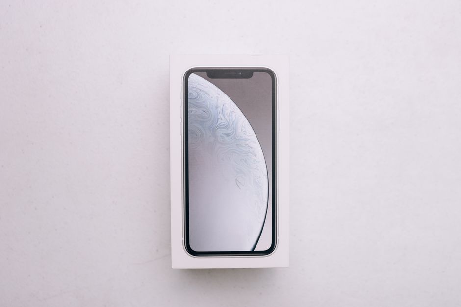 Still life editorial tech: smartphone, consola de videojuegos y reloj inteligente dispuestos sobre una superficie oscura con luz resaltando sus pantallas.